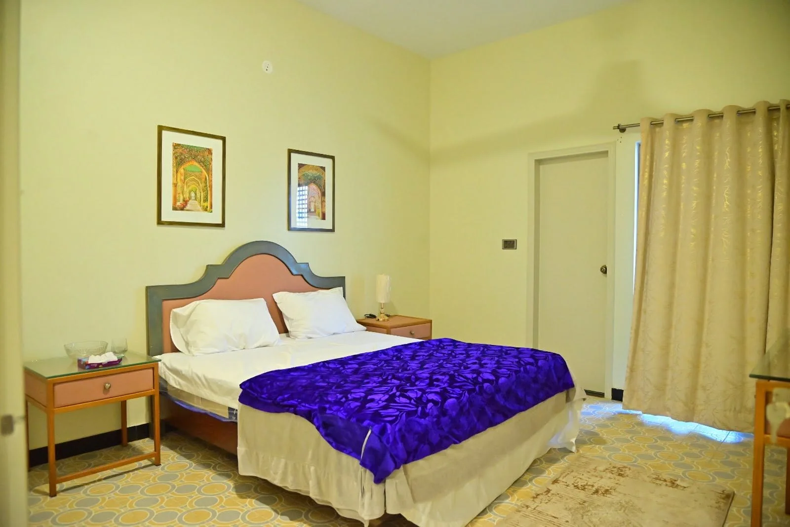 Spacious lodge bedroom with a king bed, bedside lamps and framed artwork at Shaadman Lodges & Resort